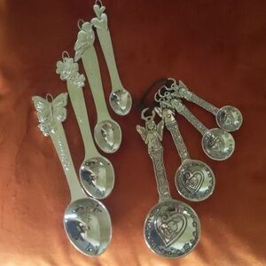 2 sets of silver measuring spoons. Angel and Garden motifs.